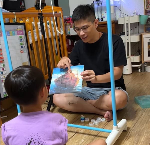 阿駿與外甥一起看著手繪的船隻圖畫